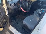 the interior of a small car with the door open and the driver ' s seat down