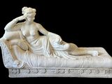 statue en marbre représentant une femme allongée sur un canapé, avec un homme assis dessus