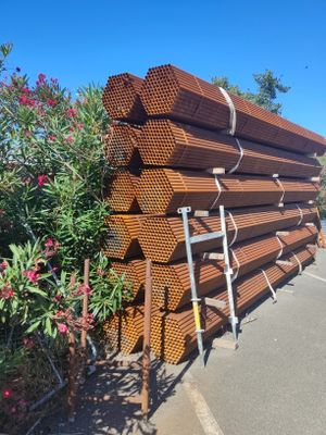 une grande pile de tuyaux en acier empilés les uns sur les autres dans un parking