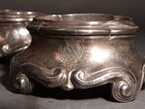 two silver pots with designs on them on a table