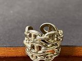 bague en argent sterling posée sur une surface en bois avec un fond gris