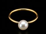 une bague en or ornée d'une perle blanche sur fond noir