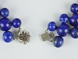 two strands of blue beads with silver clasps on a white surface