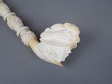 a white pipe with a carved handle on a gray surface