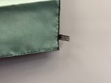 a green pillow with a tag on it on a white wall
