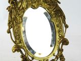 un miroir doré orné d'un oiseau, posé sur un socle