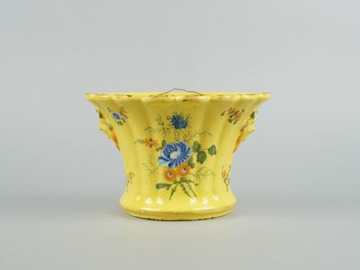 une image représentant un vase jaune orné de fleurs bleues