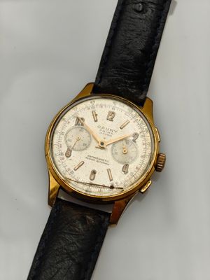 gros plan d'une montre sur une surface blanche avec un bracelet noir