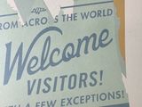 a sign that says welcome visitors with a picture of the statue of liberty in the background