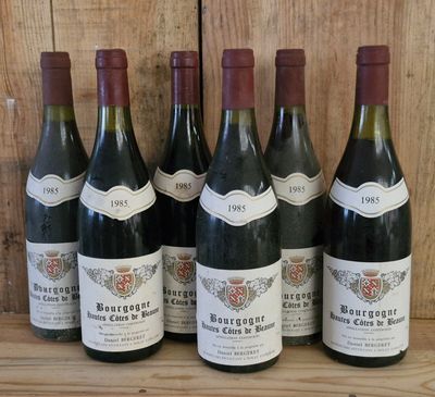 six bottles of wine are lined up on a wooden shelf