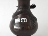a brown vase with a bird on it sitting on a table