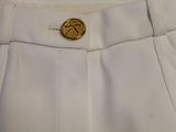 the back of a white pants with a gold button on it