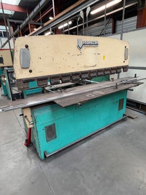 une grosse machine est entreposée dans un entrepôt où se trouve beaucoup d'acier