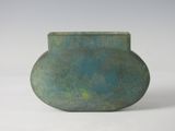 un vase vert posé sur une surface blanche