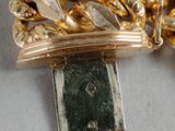 a close up of a gold chain bracelet on a white surface