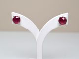 une paire de boucles d'oreilles à clous en rubis, présentée sur un socle blanc