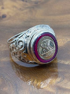 silver ring with a red stone in the center on top of a wooden table