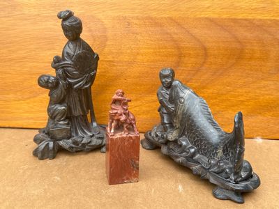 trois figurines représentant une femme et un poisson posées sur une table