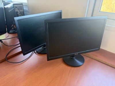 three computer monitors sitting on a desk in front of a window