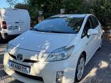 une Toyota Prius blanche garée sur un parking à côté d'une camionnette