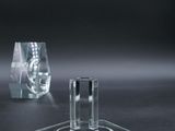 two clear glass candlesticks on a black surface with a black background