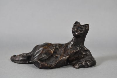 bronze sculpture of a cat laying down on a gray surface