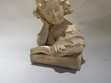 une statue représentant un enfant en train de lire un livre posé sur une table