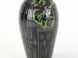 un vase noir orné de motifs verts sur fond blanc