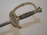 a sword with a gold handle on a white surface