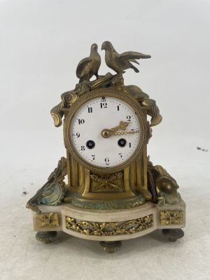 a clock with two birds on it sitting on a table