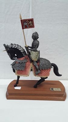 figurine of a knight on a horse with a flag on a wooden base