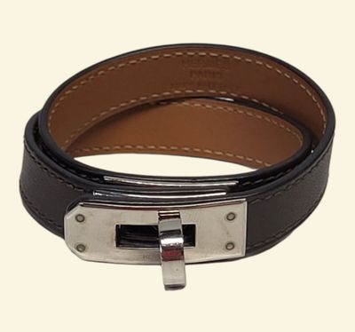 une ceinture en cuir noir avec une boucle argentée sur fond blanc