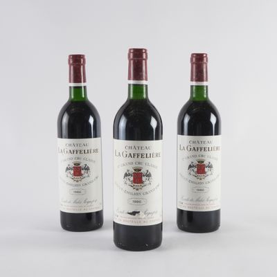trois bouteilles de vin rouge posées l'une à côté de l'autre sur une surface blanche