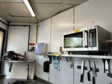 a microwave on a shelf in a kitchen with knives on the counter