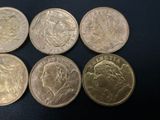 six different british coins sitting on a black surface
