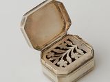 a small silver box with a flower design on it