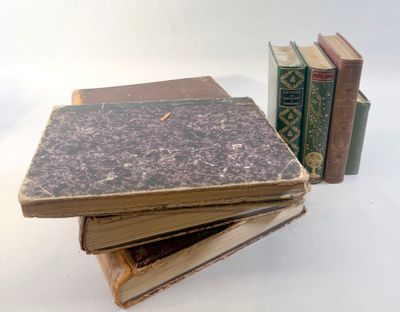 several old books stacked on top of each other on a white surface