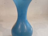 a blue vase with a gold rim sitting on a white surface