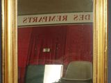 un miroir à cadre doré avec un rideau rouge en arrière-plan