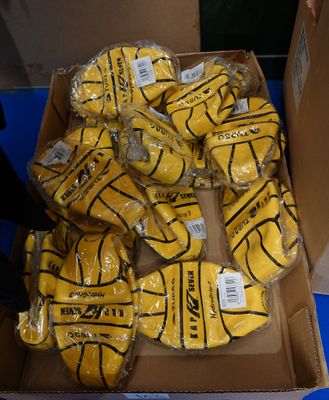 une boîte remplie de ballons de basket jaunes emballés dans du plastique
