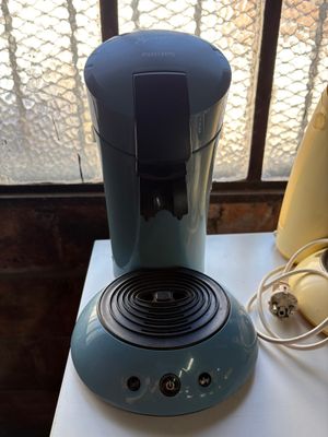 a blue coffee maker sitting on a table next to a banana