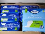 several packs of tena comfort minis in a cardboard box