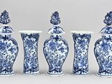 quatre vases bleus et blancs sont alignés sur un fond gris