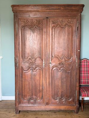 une armoire en bois dans une pièce où se trouve une chaise à carreaux