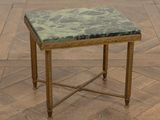 une petite table avec un plateau en marbre posée sur un parquet