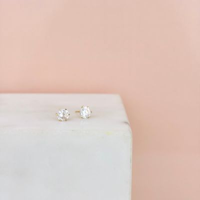 une paire de boucles d'oreilles à clous en diamant posée sur un bloc de marbre