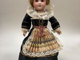 une poupée ancienne en porcelaine représentant une femme vêtue d'une robe et d'un bonnet