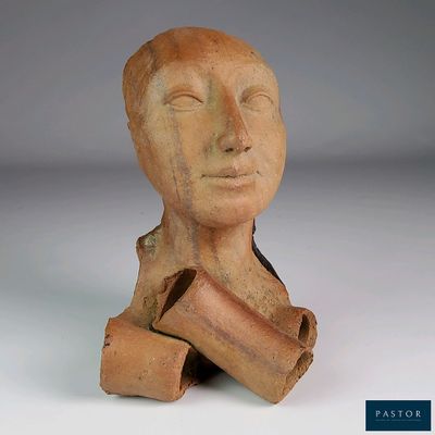 une sculpture en argile représentant une tête d'homme d'où dépasse un morceau de bois