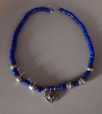 un gros plan d'un collier bleu orné de perles argentées posé sur une table