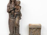 an old statue of a woman holding a child next to a small box